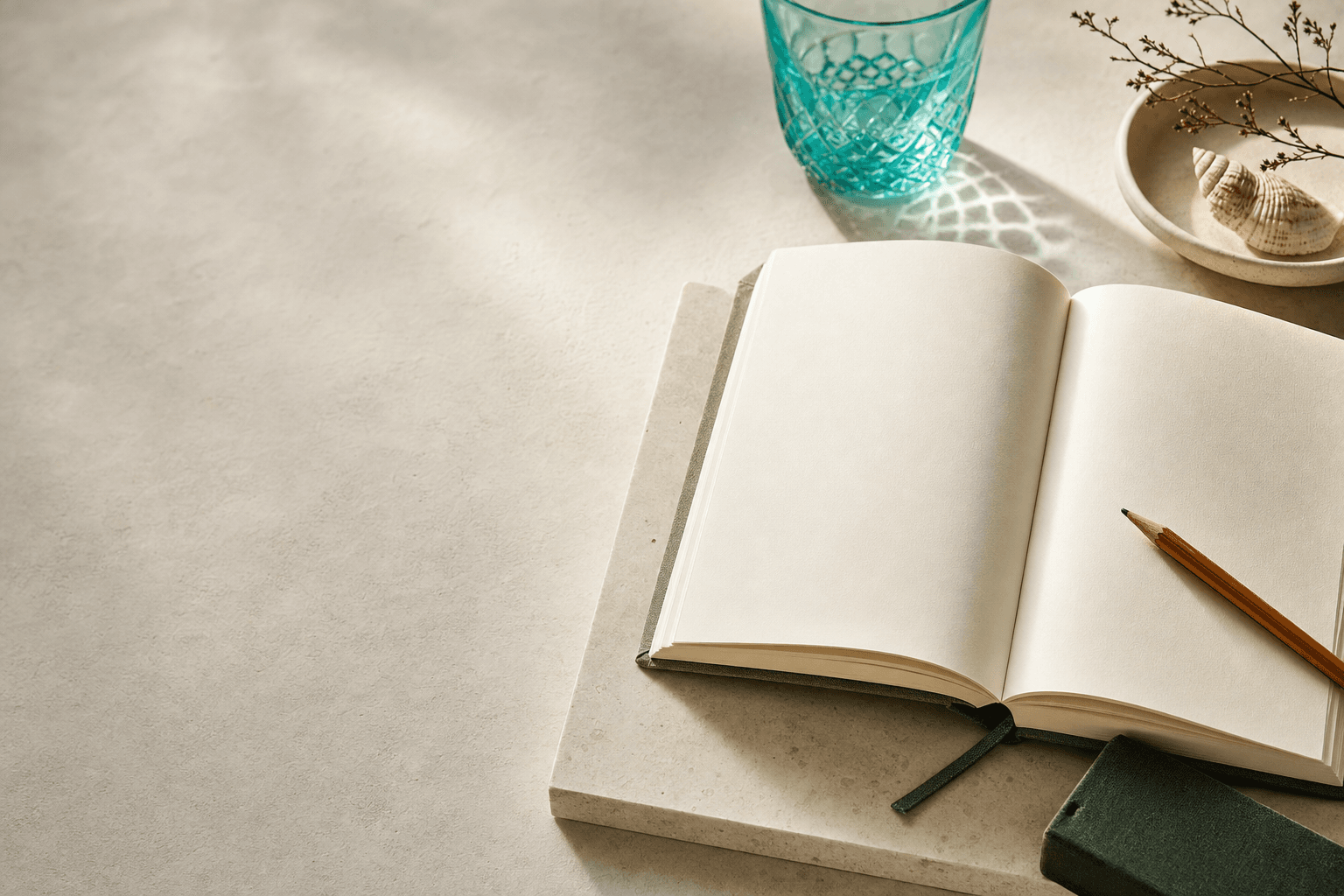A quiet desk with a notebook, glass object, and soft morning light